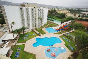 
a park with a pool, lawn chairs, and a large building at Kenzi Europa in Agadir
