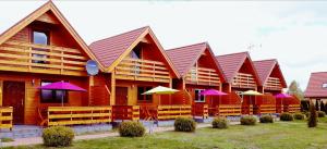 a row of buildings with pink and yellow umbrellas at Domki na Różanej 2 in Rowy