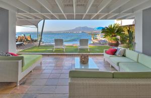 a patio with a couch and chairs and the ocean at 185 on BEACH Boutique Suites in Gordonʼs Bay