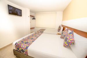 Un dormitorio con una gran cama blanca con almohadas de colores. en Hotel Portobahia Santa Marta Rodadero, en Santa Marta