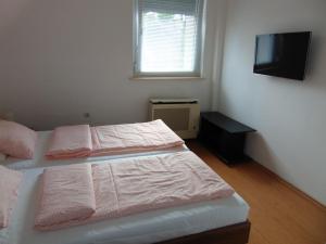 sypialnia z 2 łóżkami z różową pościelą i telewizorem w obiekcie CSEVI Apartmanház w Mezőkövesd +24 zdjęcia