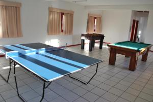 two ping pong tables in a room with two tables at Residencial Sol e Mar de Floripa in Florianópolis