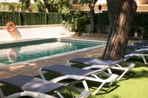 a group of lounge chairs next to a swimming pool at RVHotels Apartamentos Benelux in Platja  d'Aro