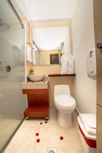 a bathroom with a toilet and a sink and a mirror at Hotel Portobahia Santa Marta Rodadero in Santa Marta
