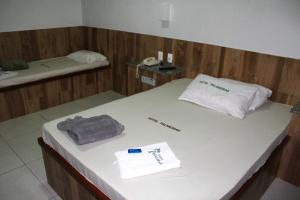 Habitación con cama con teléfono y toallas. en Hotel Palmeiras Ltda en Duque de Caxias