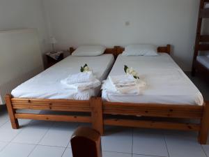 2 camas en una habitación con sábanas blancas y toallas en Pantelatos Studios en Sami