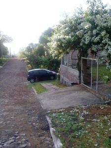 a car parked next to a house with a flowering tree at Sharing Home I in Três Coroas