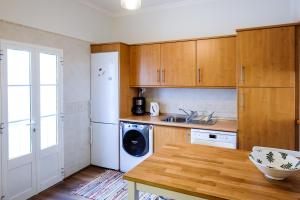 a kitchen with wooden cabinets and a washer and dryer at Casa Séqua in Tavira