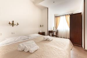 a white bedroom with two towels on a bed at Casa in Monti in Rome