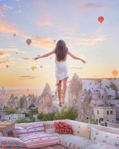 a woman jumping on top of a couch with balloons at Cappadocia Cave Suites in Goreme