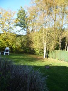 a garden with a white bench in the grass at chalet de la vallée des prés in Oignies-en-Thierache