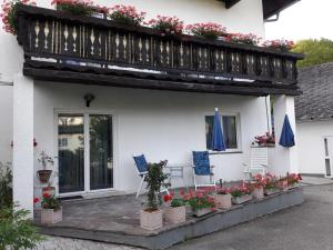 a white house with two chairs and a balcony with flowers at Villa Nusswald in Krumpendorf am Wörthersee