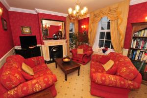 Ashtree House Bed and Breakfast في Thornton: غرفة معيشة بأثاث احمر وموقد