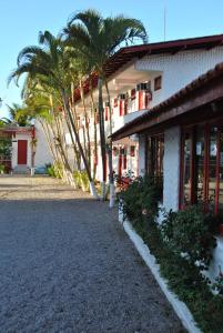 a building with palm trees next to a street at Residencial Sol e Mar de Floripa in Florianópolis