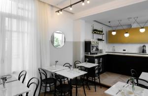 a restaurant with white tables and chairs and a kitchen at The Modernist Thessaloniki in Thessaloniki