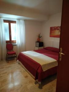 1 dormitorio con cama roja y silla roja en B&B Joy, en Colleferro