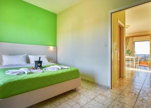 a bedroom with a bed with a green wall at Nanakis Beach Apartments in Stavros