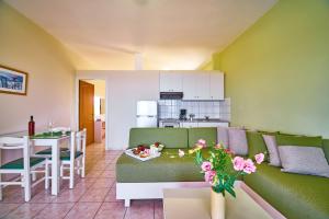a living room with a green couch and a kitchen at Nanakis Beach Apartments in Stavros
