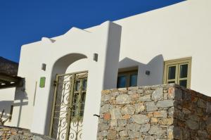 een wit huis met een poort en een stenen muur bij Vorina Ktismata in Amorgós