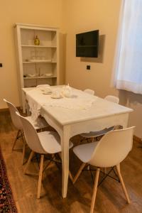 a dining room table with white chairs and a television at La Casa in Collina in Alba