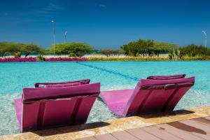 two purple chairs sitting on top of a swimming pool at Blue Residences in Palm-Eagle Beach