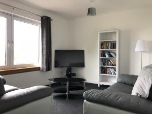 a living room with a couch and a tv at Dysart Sea View Apartment in Dysart