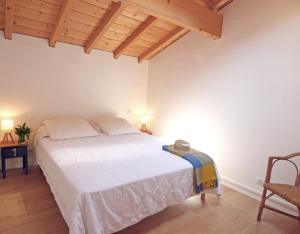 1 dormitorio con cama blanca y techo de madera en Ihi-Toki en Saint-Pée-sur-Nivelle