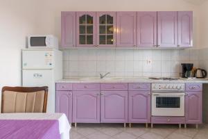 a kitchen with purple cabinets and a white refrigerator at Apartments Villa Lena in Zadar