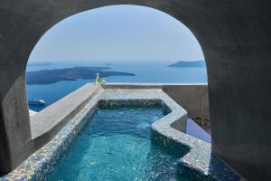 vistas a una piscina de agua desde un arco en Ventus Paradiso Villa en Imerovigli