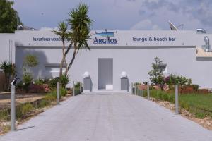 a road leading to a white building with a palm tree at Argilos in Sidari