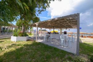 a table and chairs under a pergola on the beach at Argilos in Sidari