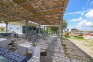 a patio with tables and chairs under a wooden roof at Argilos in Sidari