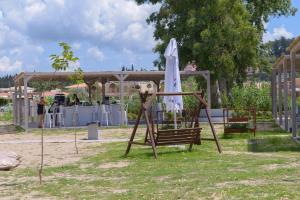 a playground with an umbrella and a swing at Argilos in Sidari
