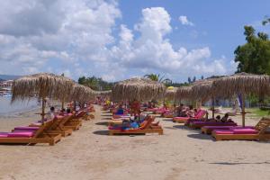 a group of people sitting on a beach with straw umbrellas at Argilos in Sidari