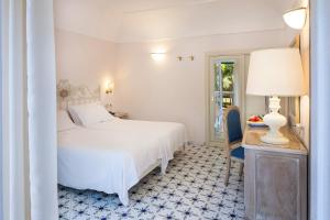 a bedroom with a white bed and a table with a lamp at Hotel Continental Ischia in Ischia