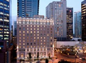 a large building in a city with tall buildings at Rosewood Hotel Georgia in Vancouver