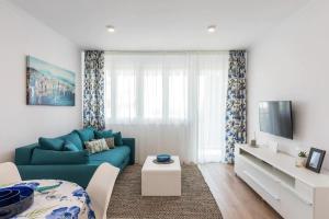 a living room with a blue couch and a tv at Relax & Recharge SEA VIEW Apartment in Split