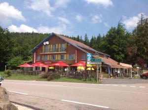 a building with tables and umbrellas on the side of a road at Relais Vosges Alsace in Plainfaing