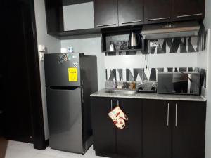 a kitchen with black cabinets and a stainless steel refrigerator at Eiffel Suite Chateau Elysee near NAIA Airport in Manila