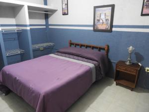 a bedroom with a bed with purple sheets and a table at La Casa Azul Hostal y Pension - Cordoba in Xalapa