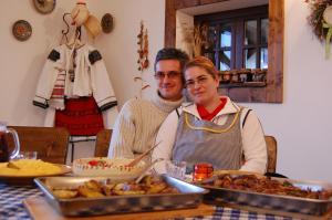 Ein Mann und eine Frau sitzen an einem Tisch mit Essen in der Unterkunft Cabana Moţilor in Mărişel