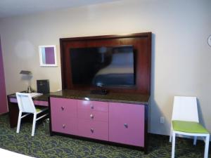 7 Springs Inn & Suites في بالم سبرينغز: غرفة مع خزانة ملابس وتلفزيون وكرسيين