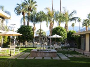 a courtyard with tables and chairs and palm trees at 7 Springs Inn & Suites in Palm Springs