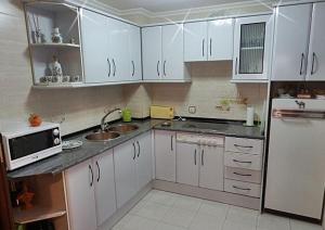 cocina con armarios blancos, fregadero y microondas en Apartamento Norte Comfort en Salamanca