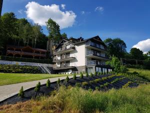 a large white house with a garden in front of it at Apartamenty Sun in Szczyrk