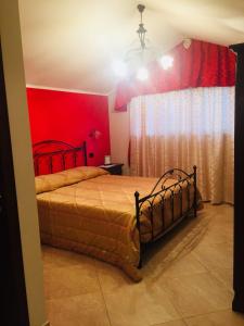 ein Schlafzimmer mit einem Bett mit einer roten Wand in der Unterkunft Agriturismo "LE ANFORE" in Ariano Irpino