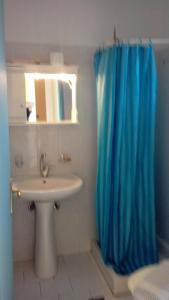 a bathroom with a blue shower curtain and a sink at Yellow house in Lassi