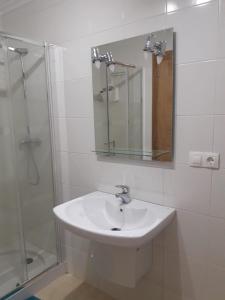 a white bathroom with a sink and a shower at Playa Caosa in San Ciprián