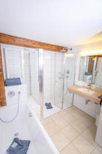 ein Bad mit einer Badewanne, einer Dusche und einem Waschbecken in der Unterkunft Bodensee Hotel Sternen in Uhldingen-Mühlhofen