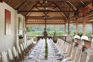a long table in a room with white chairs at The Ubud Village Resort & Spa in Ubud